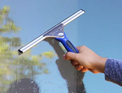 a hand holding a squeegee cleaning a window