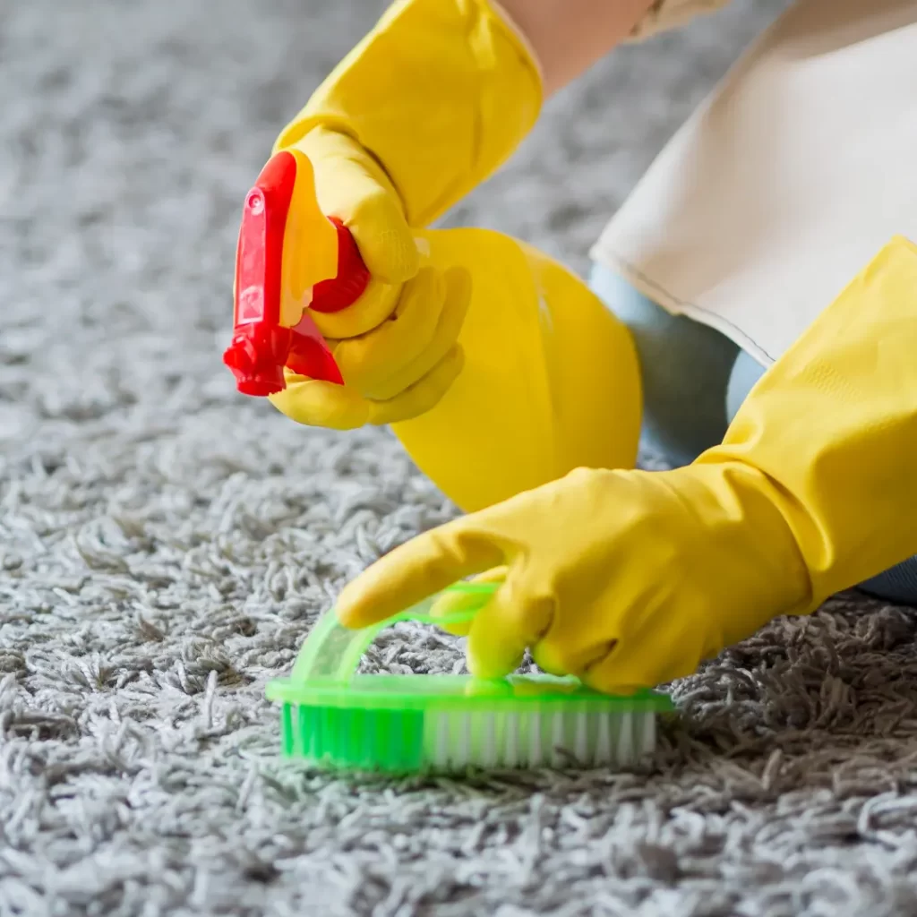 a person wearing yellow gloves cleaning a carpet