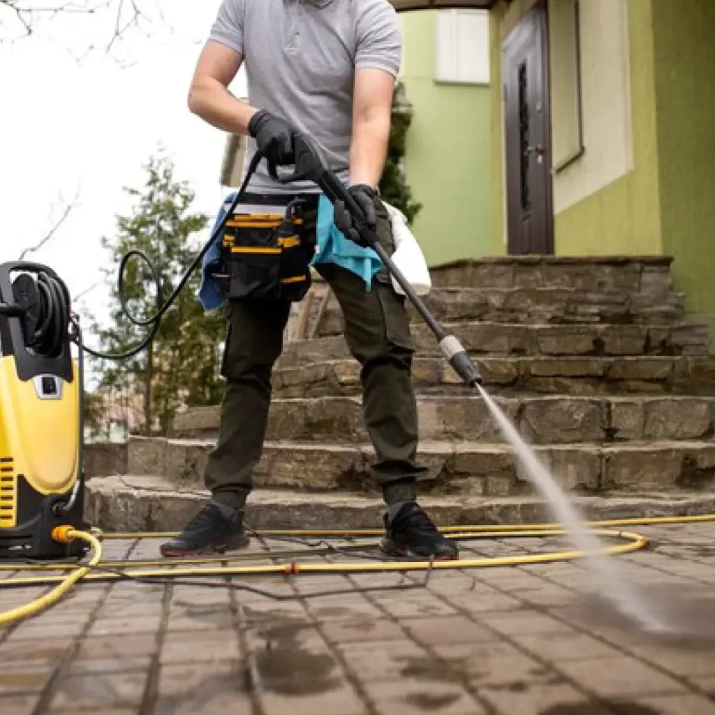 a person wearing a mask and gloves cleaning a stone walkway