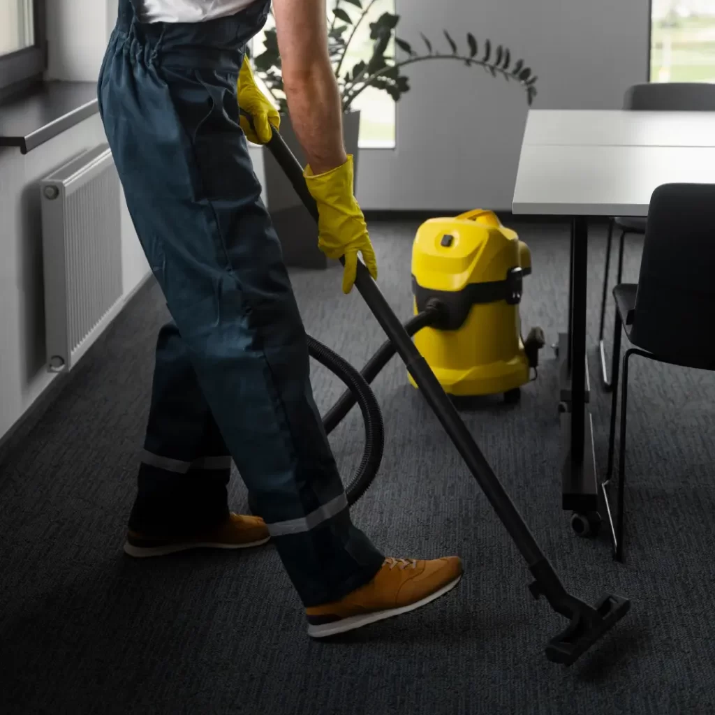 a person in a uniform vacuuming a carpet