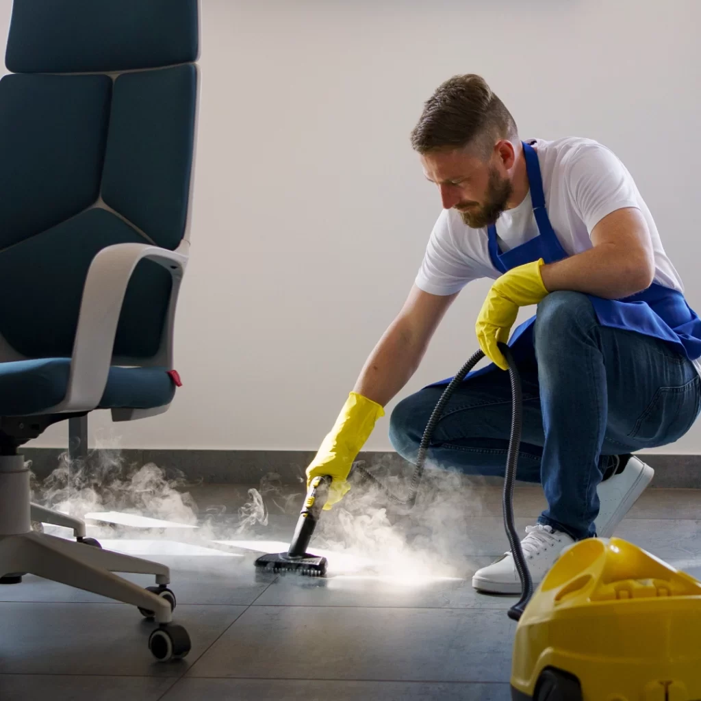 a person in a uniform cleaning a floor with steam