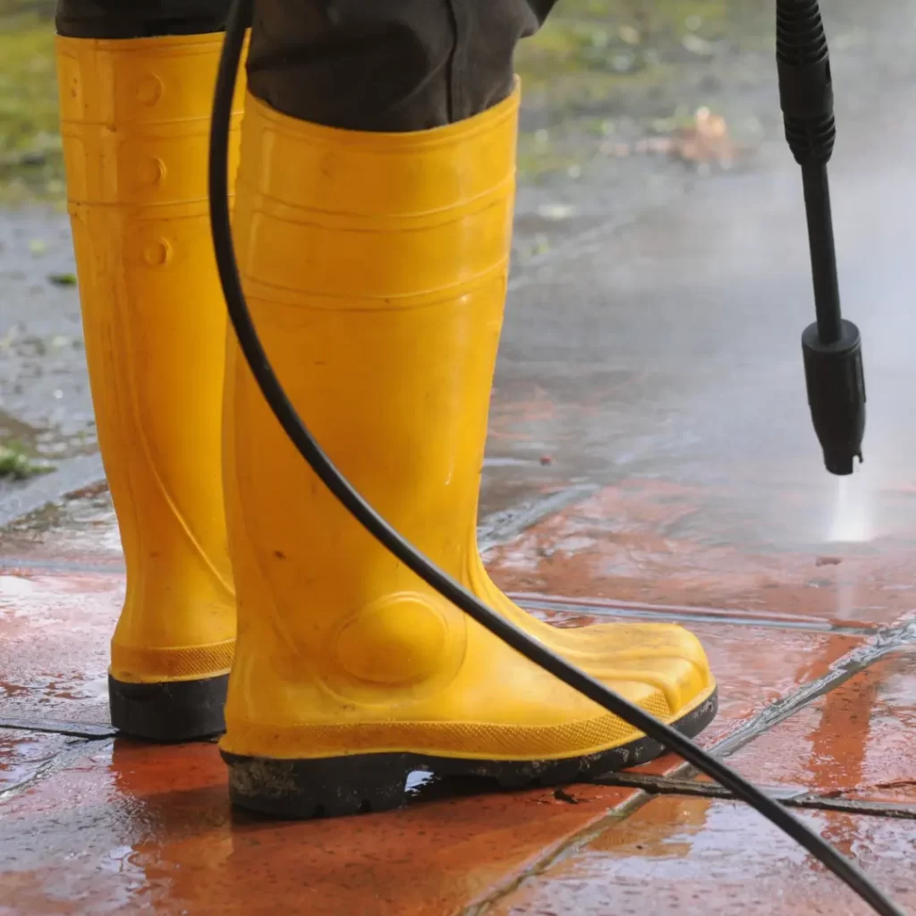 a person wearing yellow boots and holding a power washer